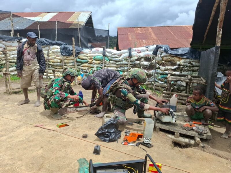 Prajurit TNI Satgas Yonif 408/Sbh membantu seorang warga memperbaiki mesin senso (chainsaw) yang menjadi alat utama untuk bekerja di Kampung Tumbupur, Distrik Kuyawage, Kabupaten Lanny Jaya, Senin (16/3/2026).